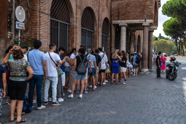 Rom - Lazio - İtalya - 08-21-2025: Bir yol kenarında seyyar atıştırmalık büfesi, içecekler ve paketlenmiş yiyeceklerle dolu bir şekilde açık dururken, bir kişi ağaçların altında ve bir lambanın altında dinleniyor.