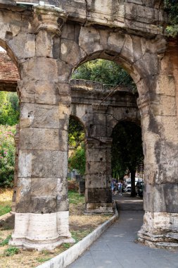 Rom - Lazio - İtalya - 08-21-2025: Bir yol kenarında seyyar atıştırmalık büfesi, içecekler ve paketlenmiş yiyeceklerle dolu bir şekilde açık dururken, bir kişi ağaçların altında ve bir lambanın altında dinleniyor.