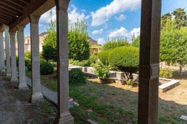 Pompei - Campania İtalya 08-25-2025: Turistler Pompei antik amfitiyatrosunun taş basamaklarını keşfederken, gruplar açık gökyüzü ve uzak dağlar altında arenada bir araya geldiler.