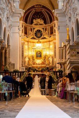 Sessa Aurunca - Campania - İtalya - 08-29-2025: Düğün töreninde Cattedrale Di Sessa 'nın iç mimarisi, gelin ve damat, konuklar beyaz koridor koşucusu boyunca otururken sunakta duruyorlar.