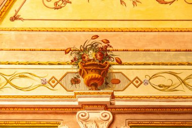 Reggia di Caserta - Campania - İtalya - 08-30-2025: Caserta Sarayı 'ndaki çiçek vazosu duvar resmi, iç kısımları sıcak sarı renklerle süslenmiş..