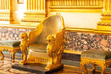 Reggia di Caserta - Campania - İtalya - 08-30-2025: Kanatlı aslan destekli altın taht koltuğu ve Caserta Kraliyet Sarayı 'nın süslü döşemelerinde yeşil döşeme.