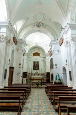 Sessa Aurunca - Campania - İtalya - 08-29-2025: Ahşap sıralar, süslemeli sütunlar, desenli fayanslar ve yanan bir sunak ile parlak bir barok kilisesinin merkezi koridoru boyunca görünüm.