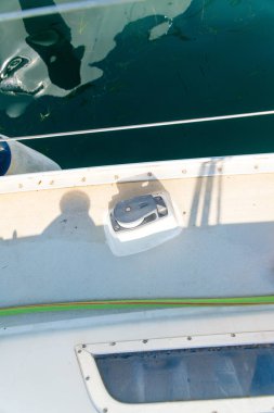 Teknenin güvertesi makara bloklu, gölgeli ve korkuluklu, su yüzeyine bitişik, güneş ışığından yansıyan yansımalarla.