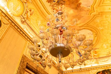 Reggia di Caserta - Campania - İtalya - 08-30-2025: Caserta Kraliyet Sarayı 'nın iç kısmındaki yaldızlı boyalı tavanın altında asılı çiçek desenli cam avize.