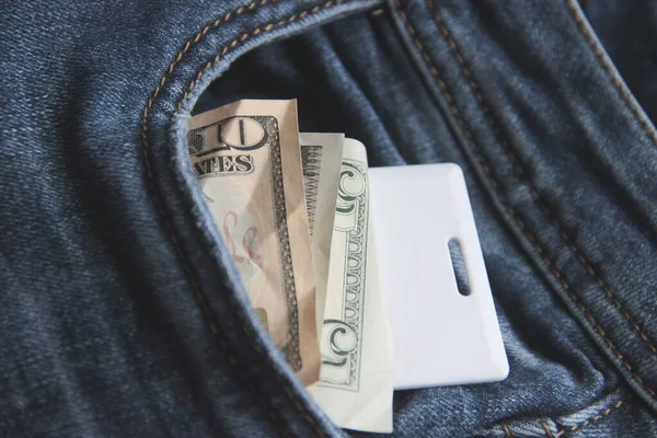 Cash and card key in a pocket of blue jeans close-up. office workers. blur — Stock Photo, Image