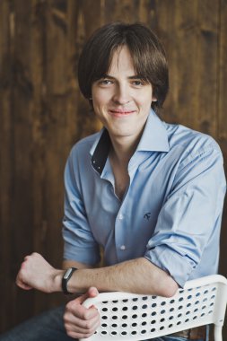 Bir adam 5457 beyaz bir sandalyede oturuyor.