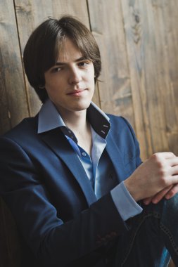 Genç bir adam ahşap duvar 5446 bir arka plan üzerinde duruyor.