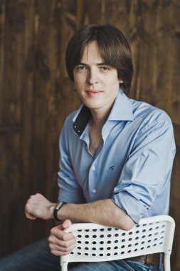 Bir adam 5456 beyaz bir sandalyede oturuyor.