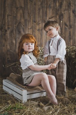 Ahşap duvarlar ve saman arka plan üzerinde elele çocuk