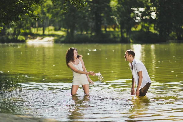 Um cara e uma garota pulverizam água na lagoa na natureza 6309 . — Fotografia de Stock