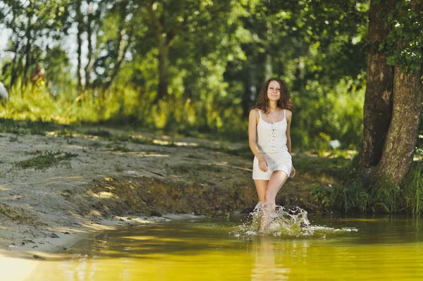 Дівчина в білій короткій сукні, ходить по краю води — стокове фото