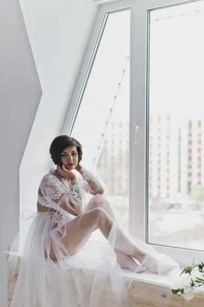 Uma bela jovem em um negligee transparente sentado em um wi — Fotografia de Stock