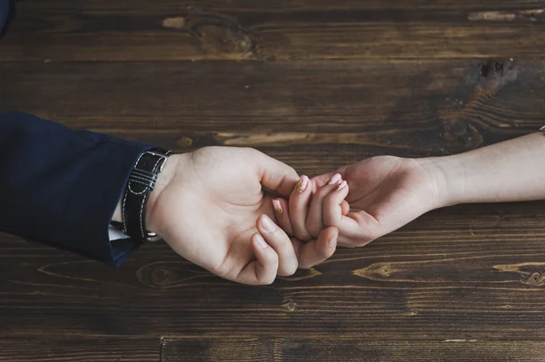 Mens hand gently holds the female on the background of wooden wa — Stock Photo, Image