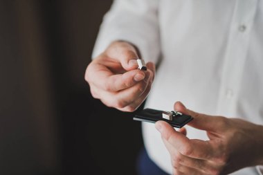 Beyaz gömlekli adam siyah kutudan gümüş kol düğmelerini aldı..