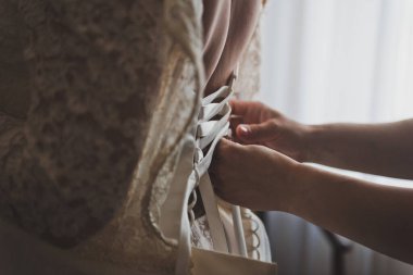 Kadınların elleri gelinliklere saten bir kurdele takar..