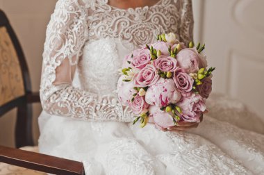 Bir buket gül ve şakayık pembe tonlarda gelinin ellerinde.