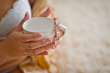 Kızların elinde beyaz bir çay fincanı.