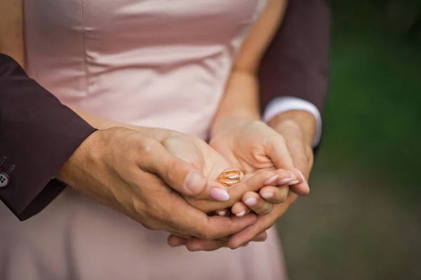 花嫁と新郎は彼らの手のひらに金の結婚指輪を保持 — ストック写真