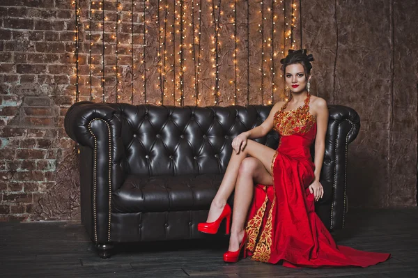 La ragazza vestita di rosso su un divano di pelle 2579 . — Foto Stock