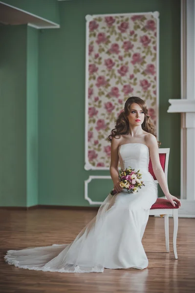 The girl in a smart dress sits on a chair in a hall 2665. — Stock Photo, Image