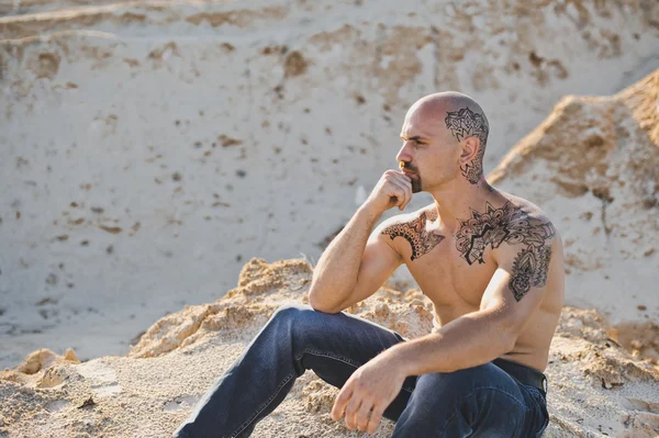 stock image The young guy sits among sand 3387.