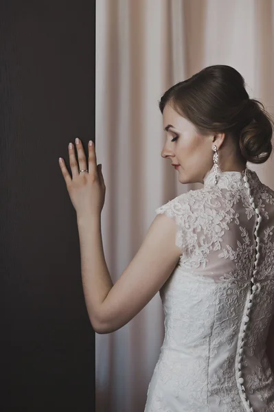 Girl in a wedding dress stands near the curtains 3857. — Stock Photo, Image