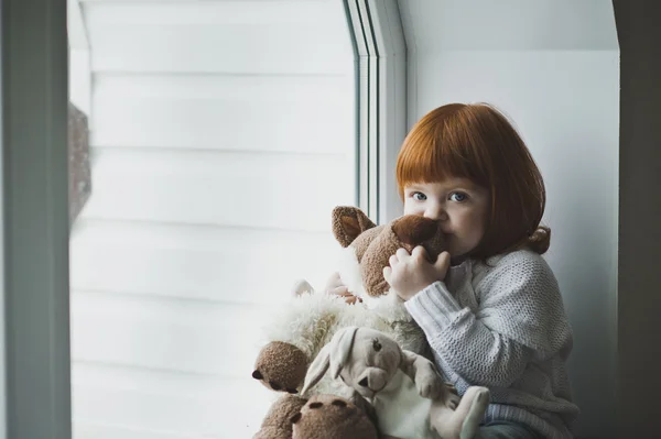 Una niña con el pelo rojo juega con el juguete 4388 . — Foto de Stock