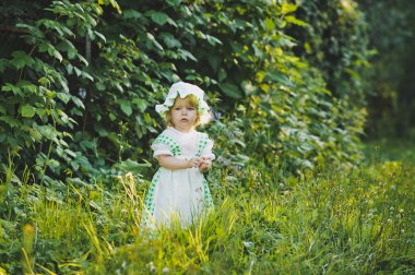 Bahçede 4648 yürüyüş yeşil ve beyaz elbiseli küçük kız.