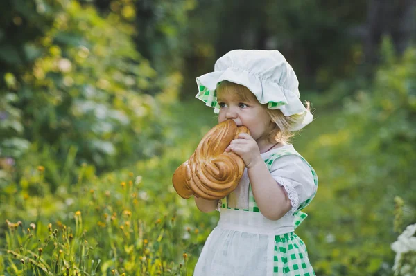 Dítě v kostýmu Kuchaři stravování bochník chleba 4627. — Stock fotografie