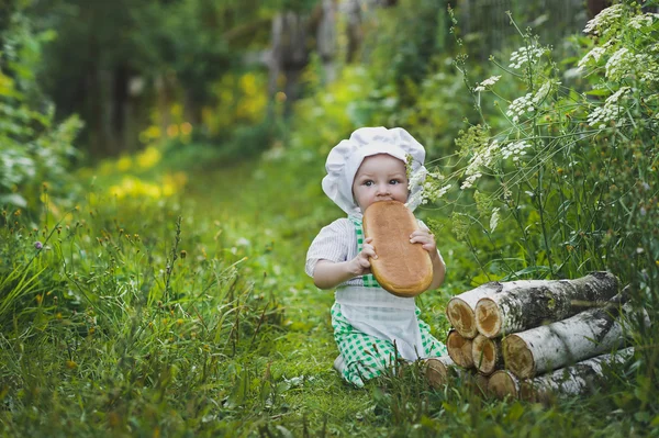 パン屋の服で子供が食べるパン 4691. — ストック写真