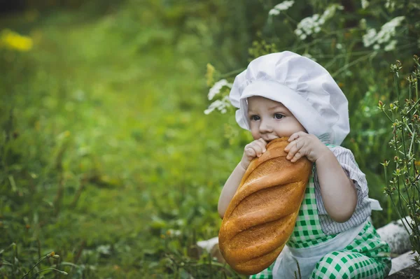 The child is eating a fresh loaf in the garden 4700. — Stock Photo, Image