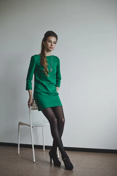 Girl in green dress standing near the chair 4885. — Stock Photo, Image