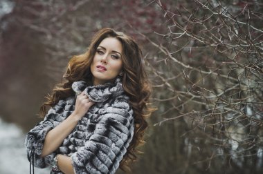 Kız kış landsca arka plan üzerinde bir fotoğraf için poz veriyor