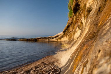 Sahilde gün batımı. Sağ tarafında taş duvar var.