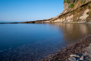 Sahilde gün batımı. Sağ tarafında taş duvar var.