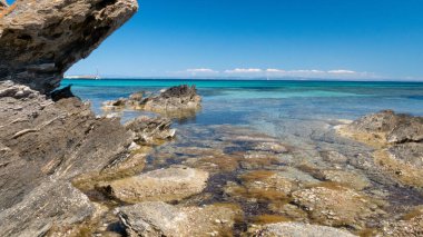 Önünde kayalar olan berrak mavi okyanus.