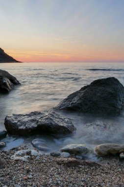 Günbatımlı bir denizde kayalar. daha uzun kepenk