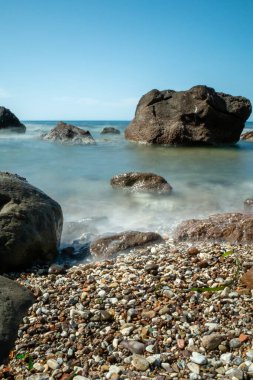 Günbatımlı bir denizde kayalar. daha uzun kepenk