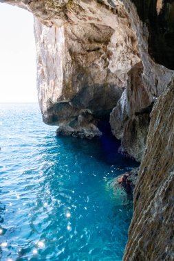 Önünde kayalar olan berrak mavi okyanus.