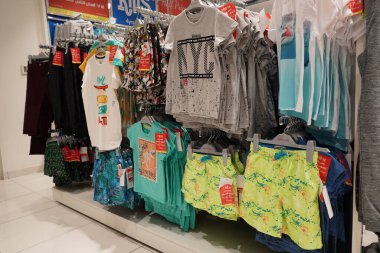 Renkli çocuk bluzları ve mağazadaki kumaş askılarda asılı tişört manzarası. Güzel kız ve erkek bebek çeşitleri süpermarkette stantlar ve askılar üzerinde giyinir. : Dubai BAE - Kasım 2020