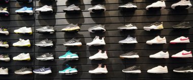 Dubai BAE Aralık 2019 - Duvarda bir sürü spor ayakkabısı sergisi. Mağazanın içinde bir ayakkabı duvarı manzarası. Modern yeni şık spor ayakkabıları erkekler ve kadınlar için koşu ayakkabıları 