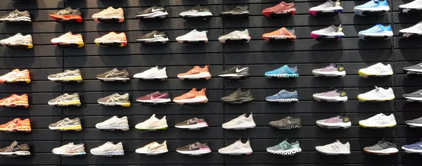 商店陈列在墙上的许多运动鞋 商店里有一堵鞋墙的景象 现代新款男女运动鞋 2019年12月 图库图片