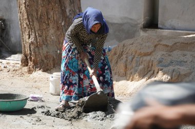 Hintli bir kadın işçi inşaat alanında ağır iş günü işinde çalışıyor. Çimentoyla harcı karıştırıyor. - Udaipur Hindistan Mart 2021 LOI