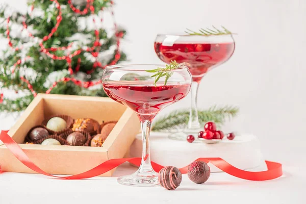 Winter drink cocktail cranberry rosemary glasses white background box chocolates