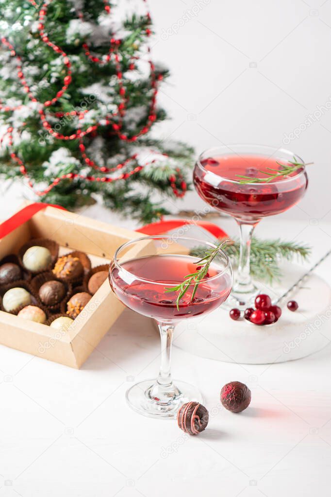 Winter drink cocktail cranberry rosemary glasses white background box chocolates