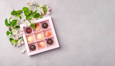 Gri arka planda, bayram kutusunda çikolatalı şekerler. Tatil kavramı