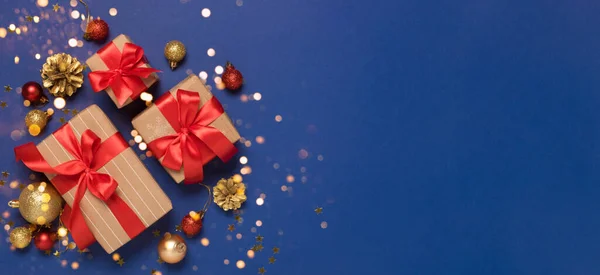 Святкові подарункові коробки червоний лук різдвяні іграшки на синьому блискучому тлі конфетті — стокове фото