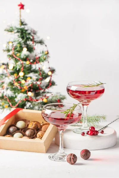 Winter drink cocktail cranberry rosemary glasses white background box chocolates Royalty Free Stock Images