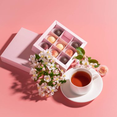 Çeşitli renklerde çikolatalı trüf şekerler. Kutlu çay, pembe arka plan.